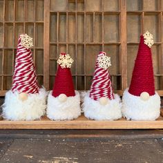 three red and white santa hats sitting on top of a wooden shelf