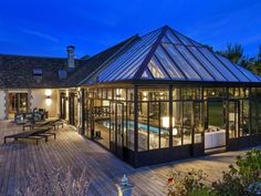 a house with a pool in the middle of it at night and lit up by lights