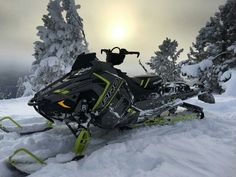 a snowmobile is parked in the snow near some trees