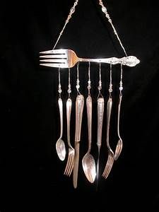 a fork, spoon and knife hanging from a metal hook on a black background with beads