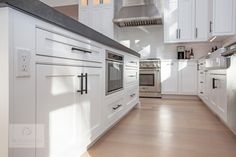 an empty kitchen with white cabinets and wood flooring is seen in this image from the doorway