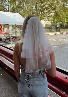 the back of a woman's head with a veil over her shoulder and jeans on