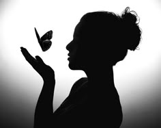 the silhouette of a woman holding a butterfly in front of a purple and red background