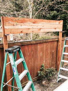 two ladders are next to a wooden fence