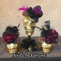 three skulls with flowers and feathers on top of a table