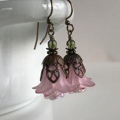 "Pretty in Pink... Add some spring to your wardrobe with these lovely double pink blossoms. Delicate pink petals surround bright pink and white centers. Antique brass filigree caps adorn the tops and a tiny green bead adds a bit of spring pop. These earrings are very lightweight and comfortable to wear. Perfect for a garden wedding, or a gift for a nature lover. And don't forget...Mother's Day is just around the corner. Drop length from bottom of antique brass french earwire: 1\" (25mm) Prefer a Feminine Pink Jewelry With Handmade Flowers, Pink Handmade Flower Earrings For Spring, Pink Earrings With Handmade Flowers For Spring, Spring Pink Earrings With Handmade Flowers, Pink Petal-shaped Earrings For Spring, Pink Feminine Dangle Flower Earrings, Pink Feminine Flower Dangle Earrings, Delicate Pink Flower Earrings For Spring, Feminine Pink Dangle Flower Earrings