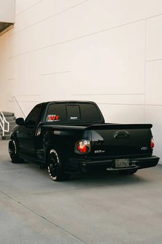 a black truck parked in front of a white building next to a stair case and stairs