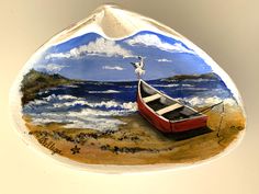 a painted glass ornament with a boat on the beach