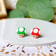 two small mushroom shaped studs sitting on top of a white table next to a green plant