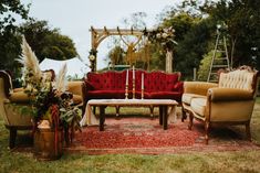 a red couch sitting on top of a lush green field