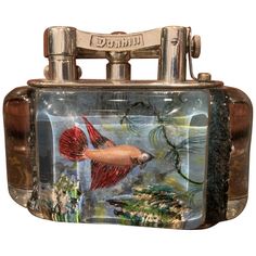 a small metal box with a painting on it's front and sides, in the shape of a fish