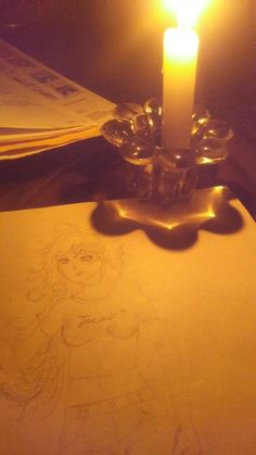 a lit candle on top of a piece of paper with a drawing of a girl