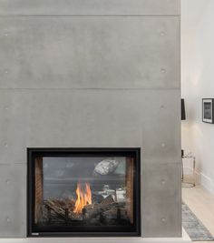 a fire place in the middle of a living room with concrete walls and flooring