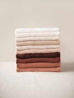 a stack of folded towels sitting on top of a white tablecloth covered in various colors