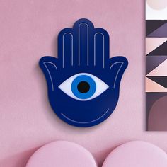 a blue hamsa hanging from the side of a wall next to two pink circles