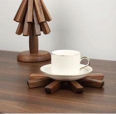 a white cup and saucer on a wooden table with a small tree shaped object in the background