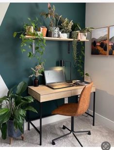 a laptop computer sitting on top of a wooden desk next to a potted plant