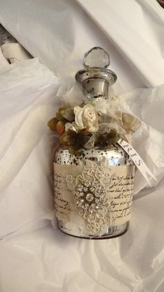 a jar with some flowers on it sitting on a white cloth covered tablecloths