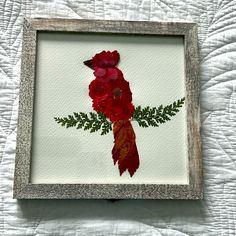 a red bird sitting on top of a white bed next to a wooden framed object