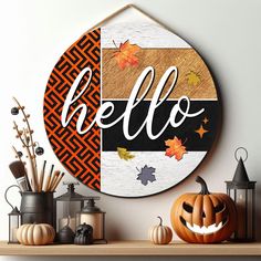 a wooden sign with the word hello painted on it next to pumpkins and candles