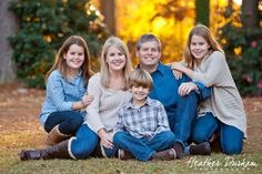 a family sitting on the ground in front of some trees