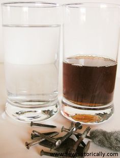 two glasses filled with liquid and screws next to each other on a white surface