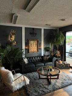 a living room filled with black furniture and lots of plants on top of the couches