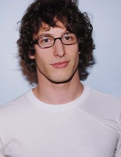 a young man with curly hair wearing glasses