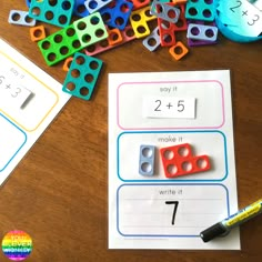 a table topped with lots of colorful legos next to some sort of writing paper