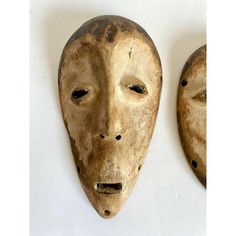 two wooden masks with holes in them on a white surface