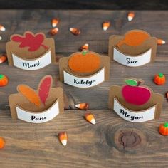 some paper pumpkins are sitting on a wooden table with labels for each individual to put in them