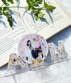 an open book sitting on top of a table next to some glass letters and flowers