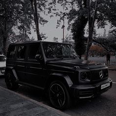 a black mercedes g - class parked on the street