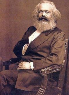 an old black and white photo of a man with a beard sitting in a chair