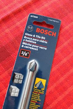 the bosch screwdriver is in its packaging on top of a red cloth with an orange background