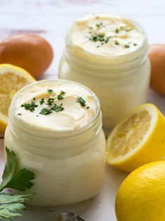 two mason jars filled with cream surrounded by lemons and parsley