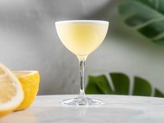 a close up of a wine glass on a table with lemons in the background