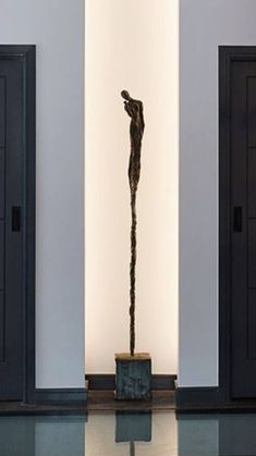 a sculpture in the middle of a room with two doors and one is standing up