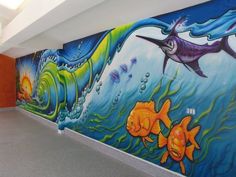 the mural is painted on the side of the building and shows different types of fish