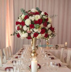 a long table with white and red flowers in a tall vase on it's centerpiece