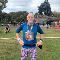 a man standing in front of a statue with his hands on his hips wearing colorful pants