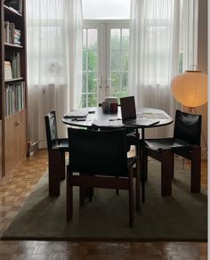 a dining room table and chairs in front of a book shelf with books on it