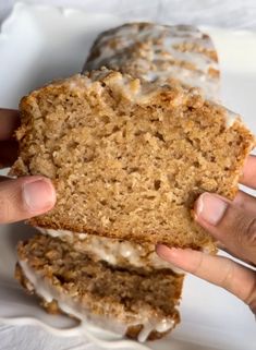 a person holding a piece of bread with icing on it in front of another