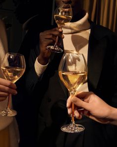 three people holding wine glasses in their hands