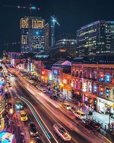 a city street filled with lots of traffic and tall buildings in the background at night