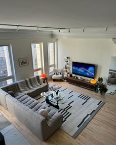 a living room filled with furniture and a flat screen tv on top of a wooden floor