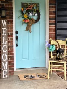 a blue front door with a welcome sign on it and a yellow chair in front