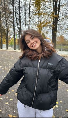 a woman is standing in the street with her hands behind her back and smiling at the camera