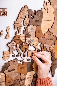 a person is holding a piece of wood in front of a map of the world