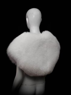 a white mannequin wearing a white fur stole on top of a black background